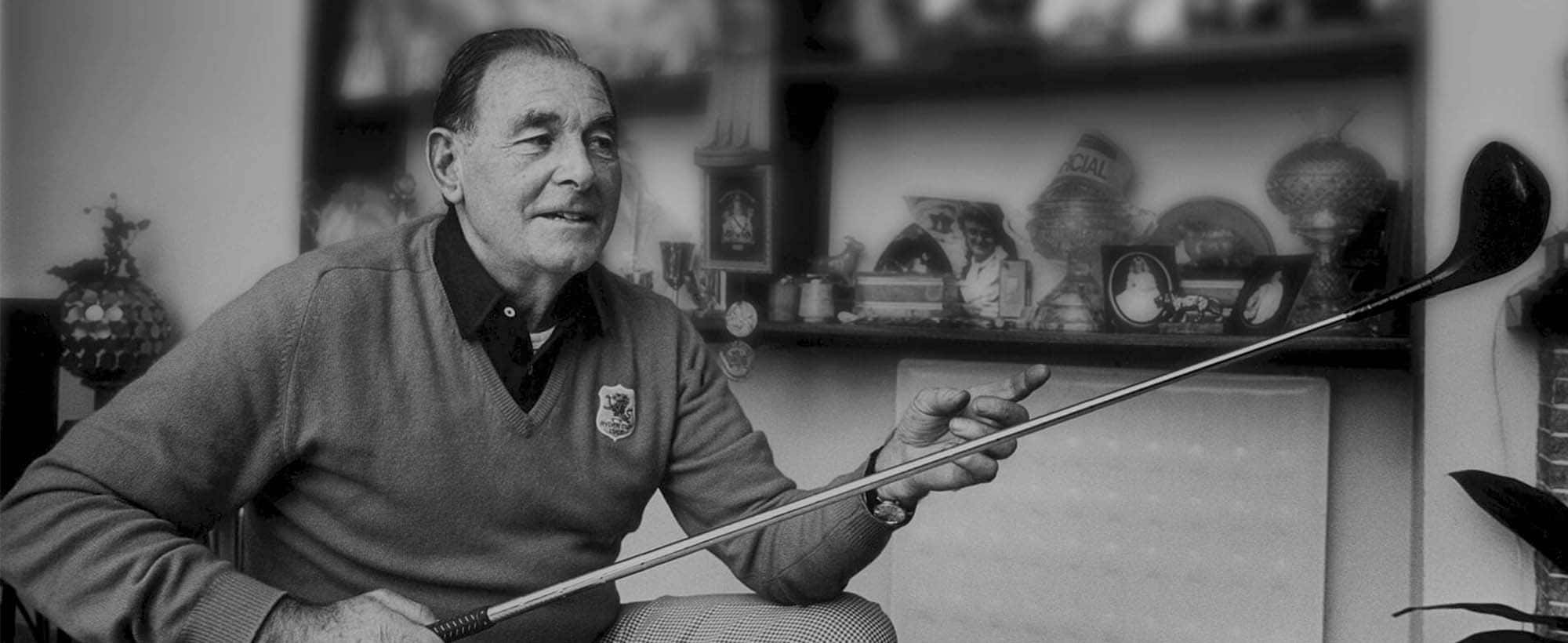 Black and white portrait photograph of Irish golfing legend Christy O'Connor Senior seated indoors holding a golf club