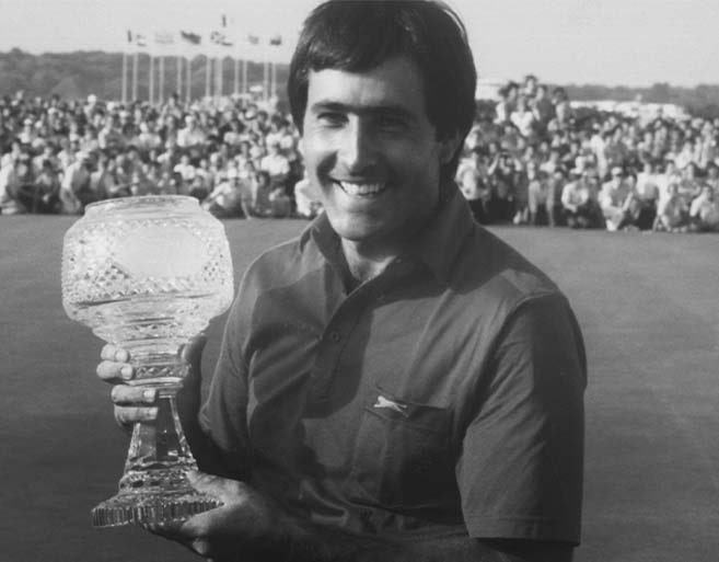 Black and white photograph of a smiling Seve Ballesteros holding a large crystal trophy after winning the Irish Open at Golf Club of Dublin, with a large crowd of spectators visible in the background