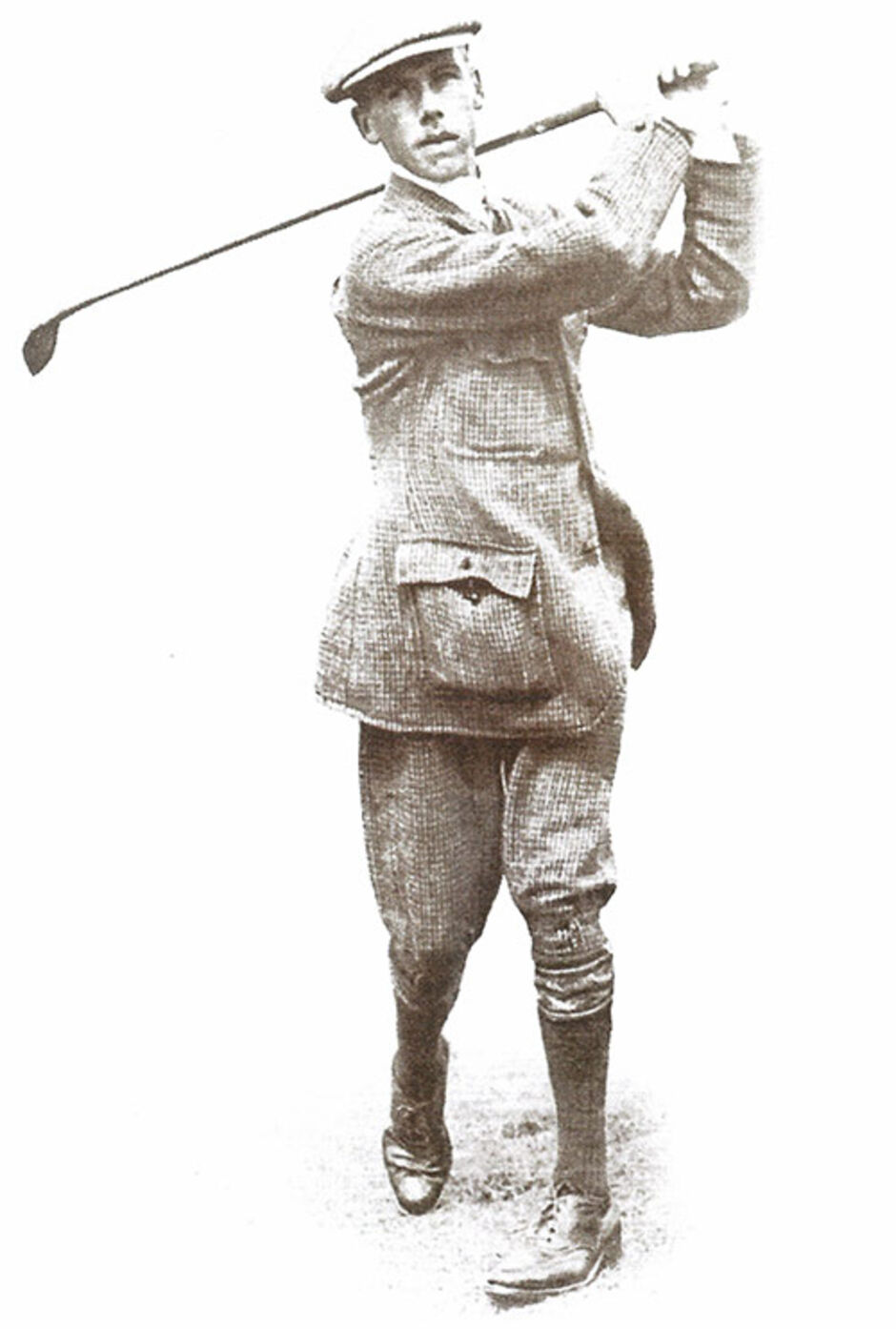 Sepia-toned early 20th-century photograph of golfer Michael Moran mid-swing, wearing traditional period attire including a flat cap, tweed jacket, plus-fours, knee-length socks, and leather shoes